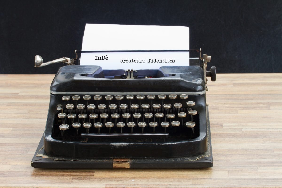 black vintage typewriter with empty white page on wooden table